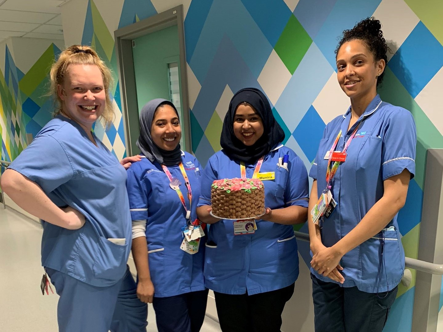Four nurses on the ward holding a cake made with donated sugar