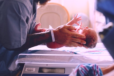 Doctor weighing a newborn baby