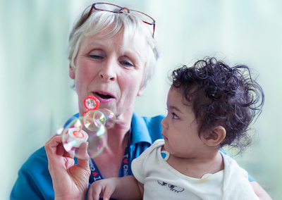 Play Team nurse blowing bubbles to entertain small child