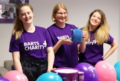 Three women in Barts Charity t-shirts raising money at bake sale