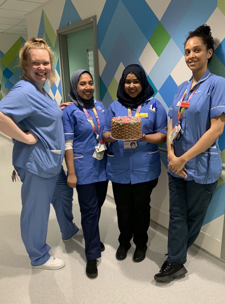 Four nurses on the ward holding a cake made with donated sugar
