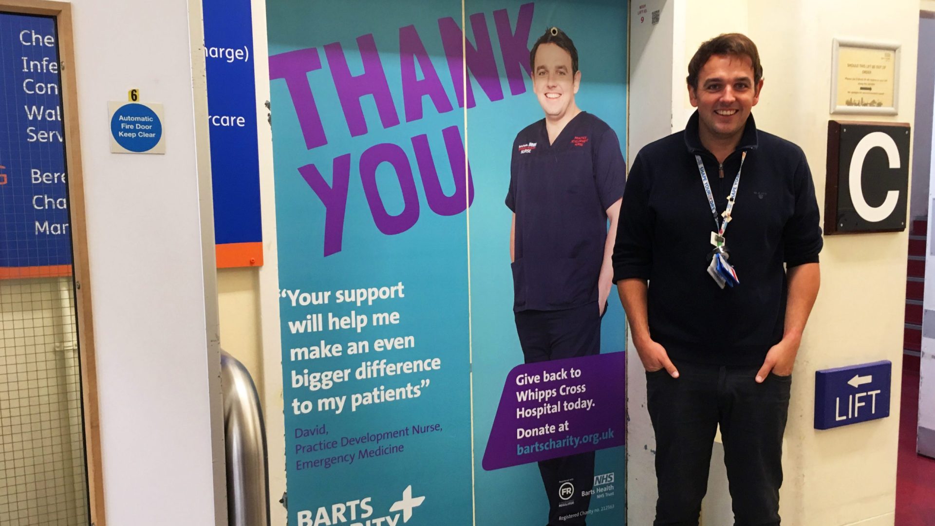 David poses next to his poster at Whipps Cross Hospital