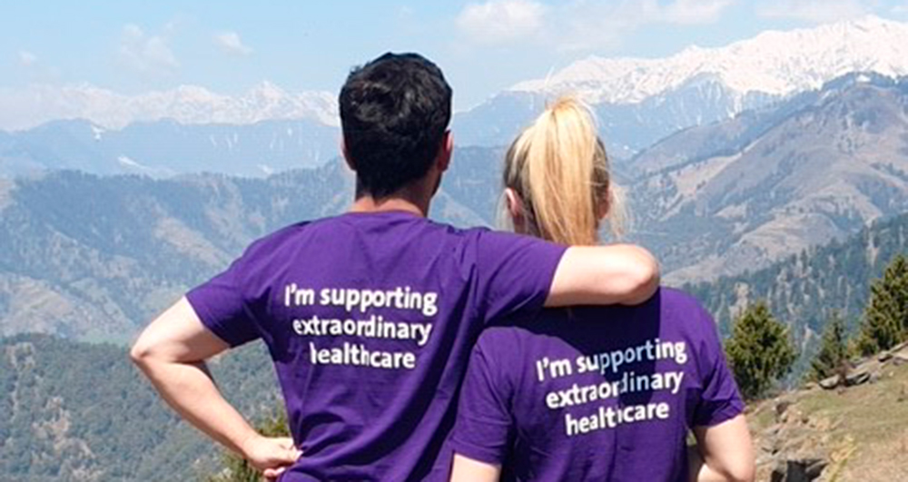 Two Barts Charity fundraisers silhouetted against the mountains they are trekking through