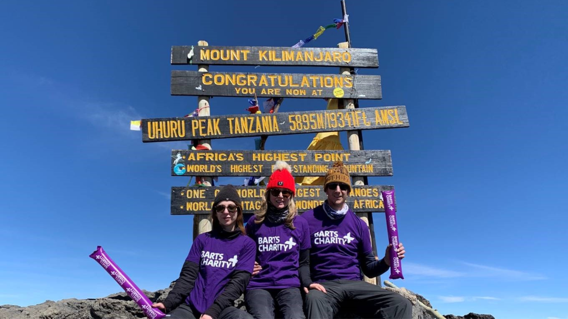 Fundraisers sitting at the top of Mount Kilimanjaro