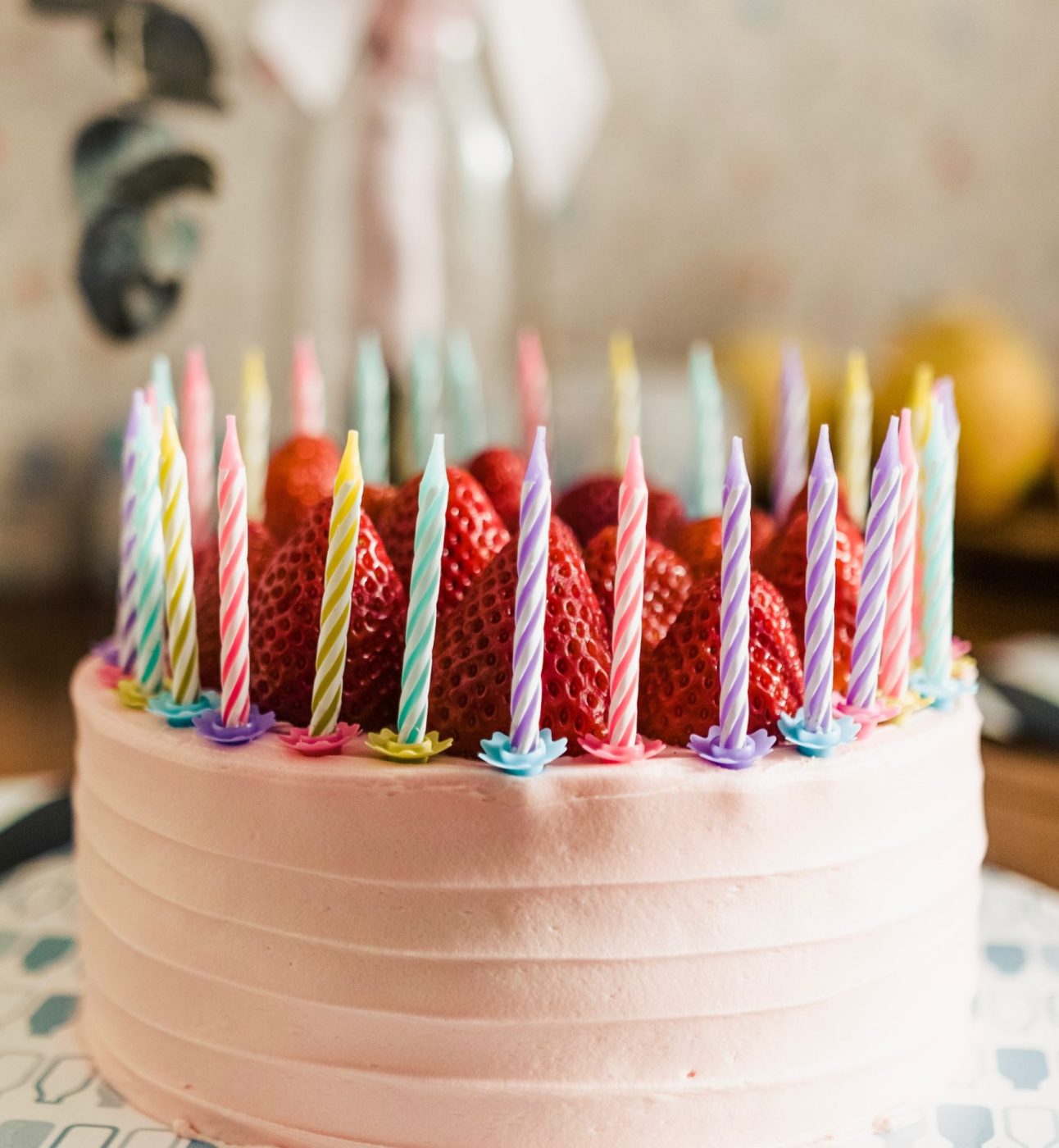 Pink birthday cake with strawberries and candles on top