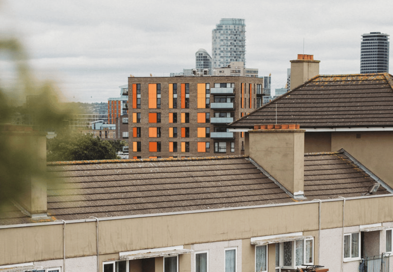 A cityscape photo with tall buildings in the background and a block of flats closer up. Setting seems to be in London on a cloudy day
