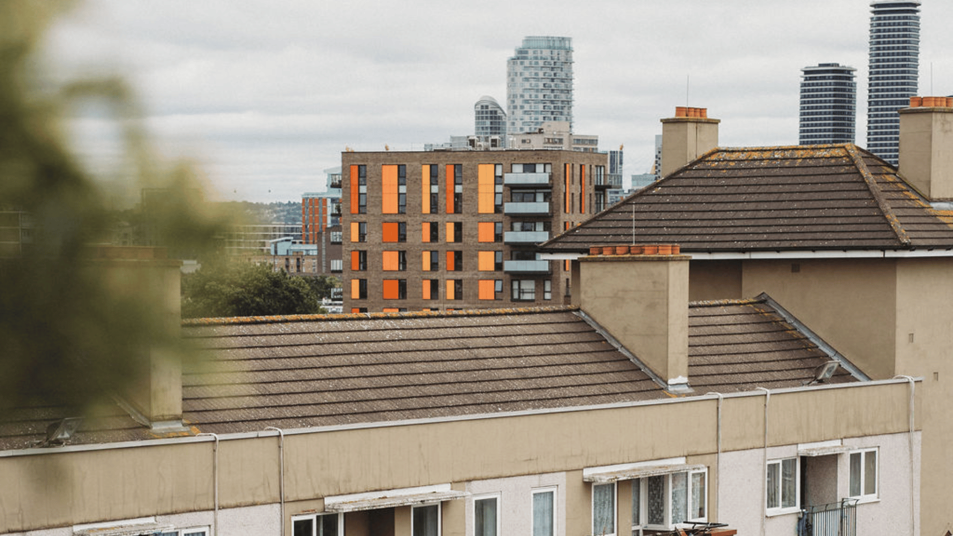 A cityscape photo with tall buildings in the background and a block of flats closer up. Setting seems to be in London on a cloudy day