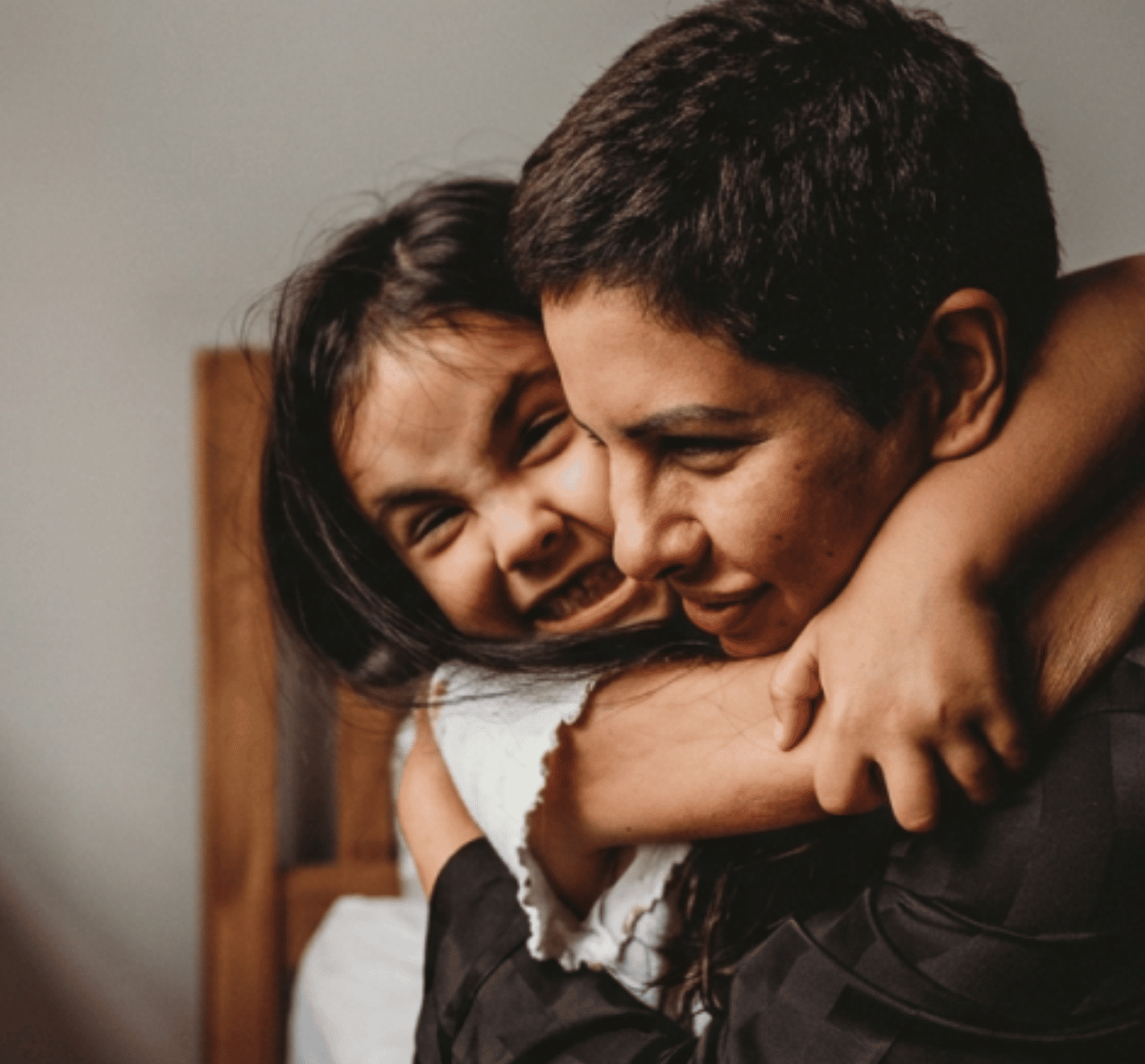 A woman and a child hugging, both smiling