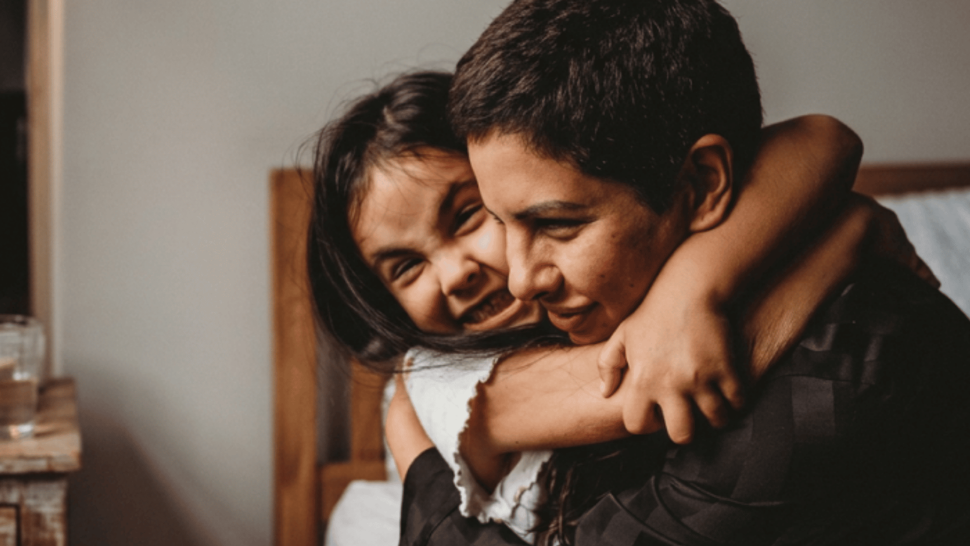 A woman and a child hugging, both smiling