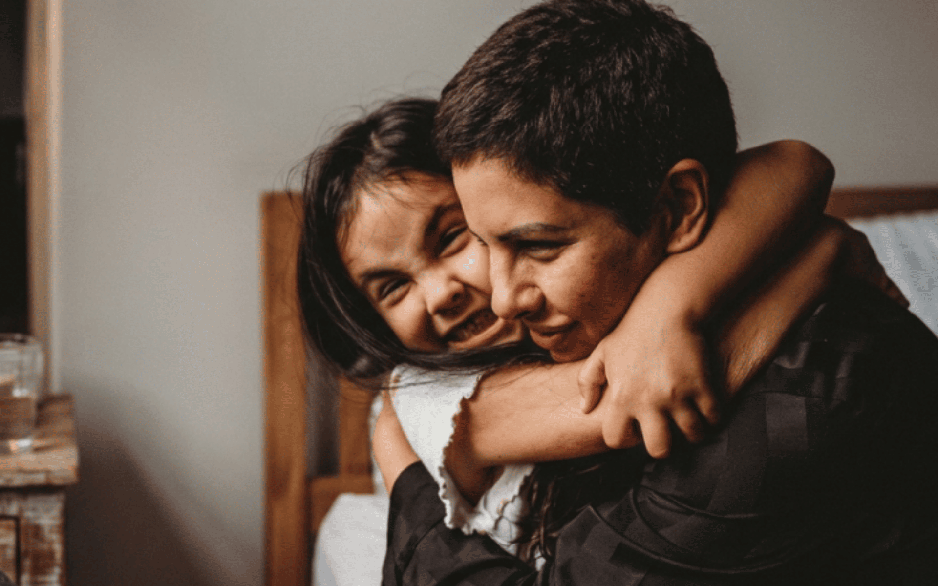 A woman and a child hugging, both smiling